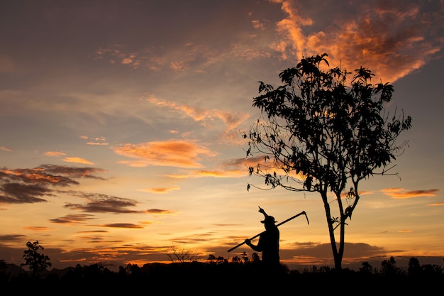 Silueta del granjero que señala en el cielo con puesta del sol en el tiempo de la tarde, concepto de la agricultura