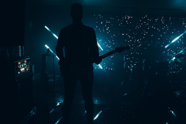 Silueta de un guitarrista en un espectacular escenario oscuro iluminado con una guitarra rock de concierto de vida nocturna