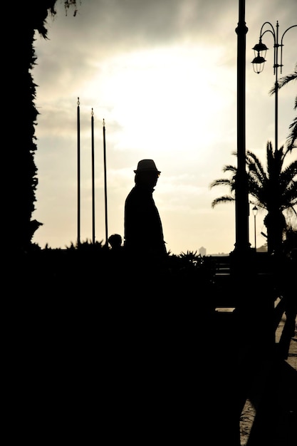 Silueta de un hombre con abrigo y sombrero en la costa del mar al atardecer Concepto de misterio o soledad Adecuado para la portada de un libro de suspenso Copiar espacio para texto