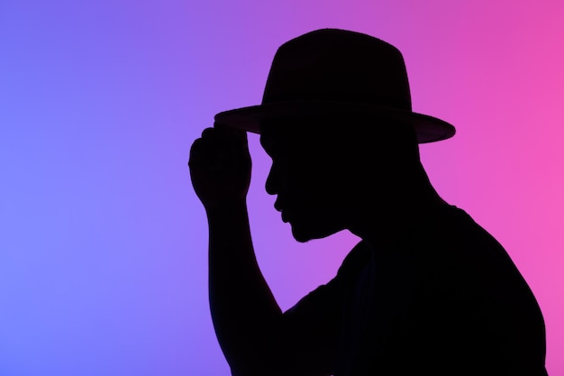 Silueta hombre afroamericano en sombrero contra el fondo de colores de neón