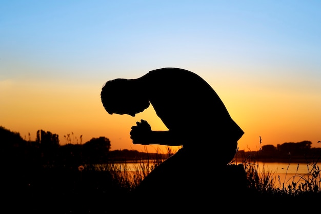 Foto silueta de hombre al atardecer orando a dios