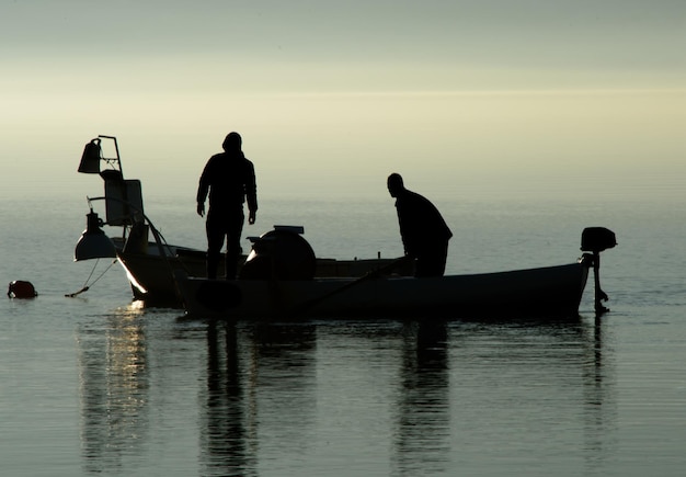 Silueta de un hombre en un barco en el mar contra el cielo