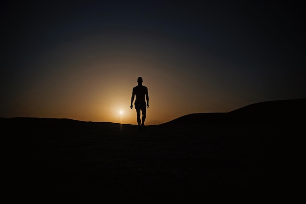 Silueta de hombre caminando en el cielo del atardecer