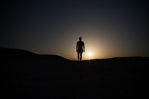 Silueta de hombre caminando en el cielo del atardecer