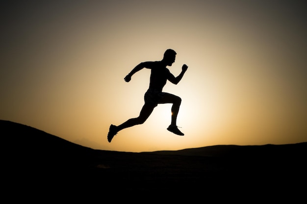 Silueta de hombre corriendo en el cielo del atardecer