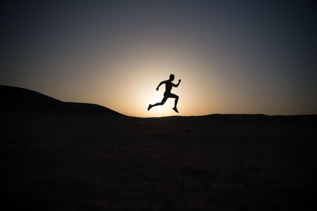 Silueta de hombre corriendo en el cielo del atardecer