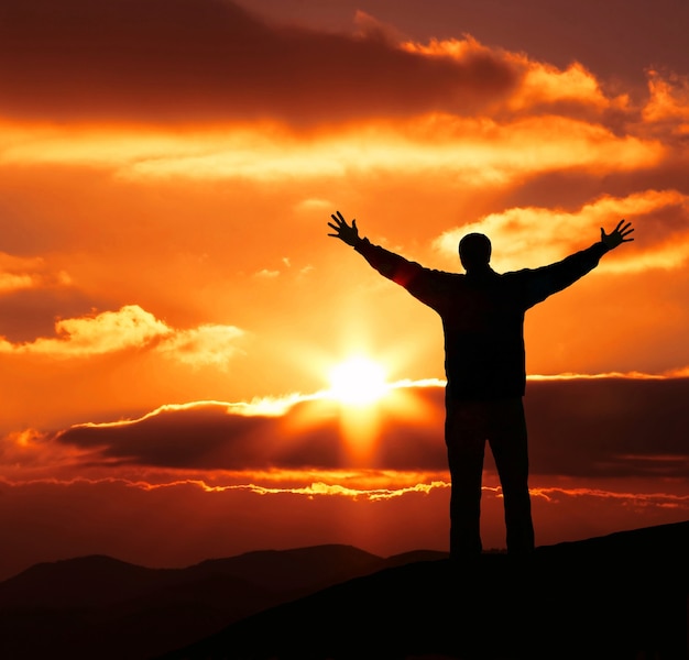 Silueta de hombre de felicidad en la puesta de sol