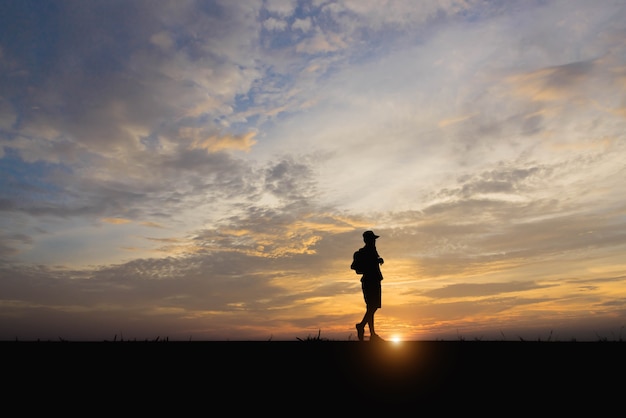 Silueta de un hombre feliz caminando al atardecer.