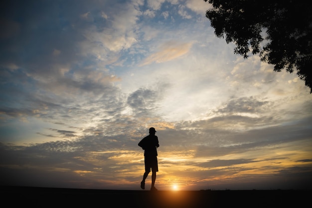 Silueta de un hombre feliz caminando al atardecer.