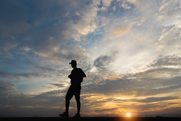 Silueta de un hombre feliz caminando al atardecer.