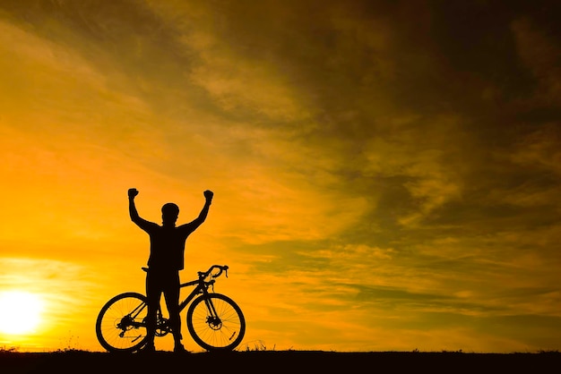 Silueta de hombre guapo montando bicicleta en concepto de hombre de deporte al atardecerEfecto de llamarada de relleno