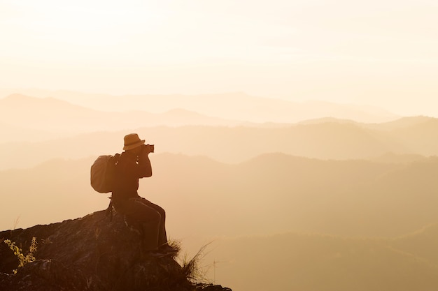 Silueta de hombre levanta las manos en la cima de la montaña, concepto de éxito