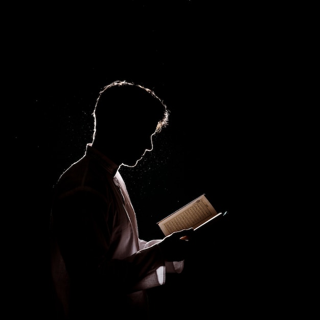 Foto silueta de hombre leyendo en corán