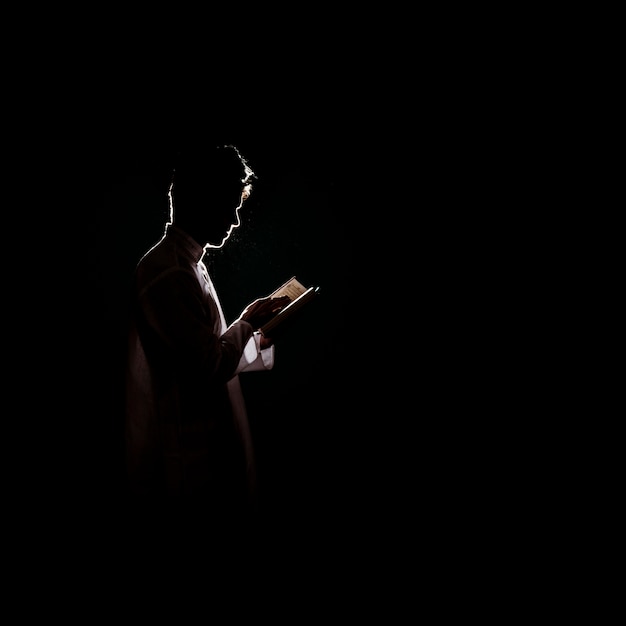 Foto silueta de hombre leyendo en corán