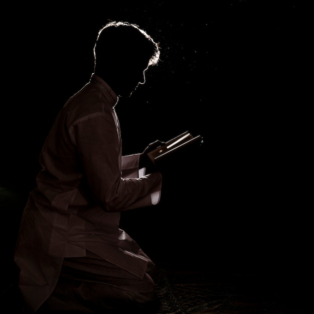 Foto silueta de hombre leyendo en corán