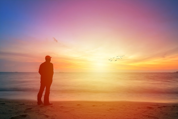 Foto silueta de un hombre mirando al hermoso cielo durante el atardecer dorado