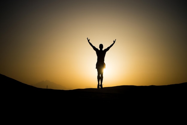 Silueta de hombre musculoso en el fondo del cielo ardiente de la puesta del sol en el futuro del deporte y la recreación de montaña y la gente de éxito y la velocidad de la naturaleza y el estilo de vida saludable yoga y fitness