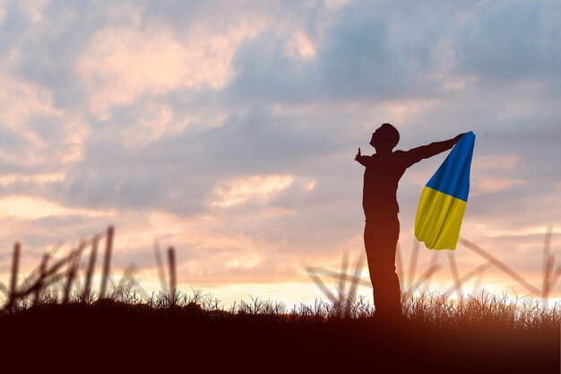 silueta, de, un, hombre de negocios, tenencia, ucrania, bandera, con, salida del sol, plano de fondo