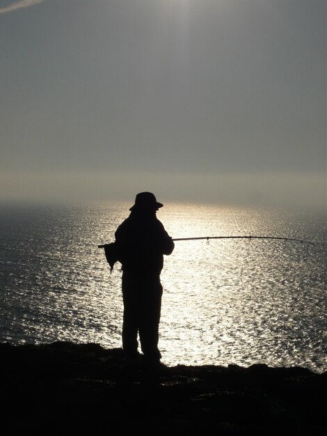 Foto silueta de un hombre pescando en el mar contra el cielo