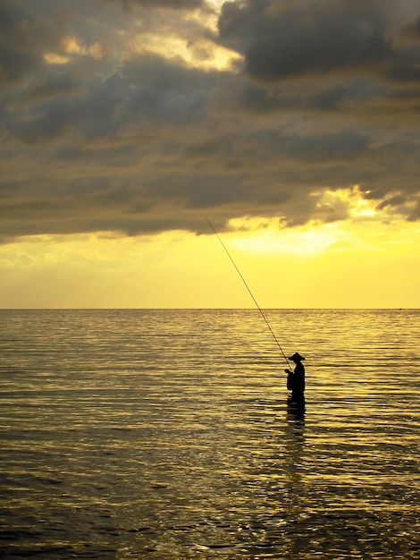 Silueta de un hombre pescando en una puesta de sol, Bali, Indonesia