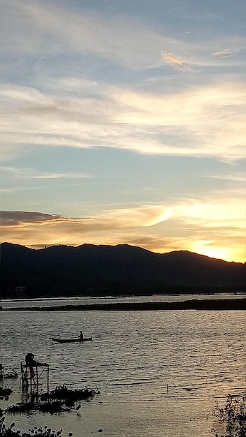 Silueta de un hombre pescando por la tarde. puesta de sol en el lago limboto, indonesia