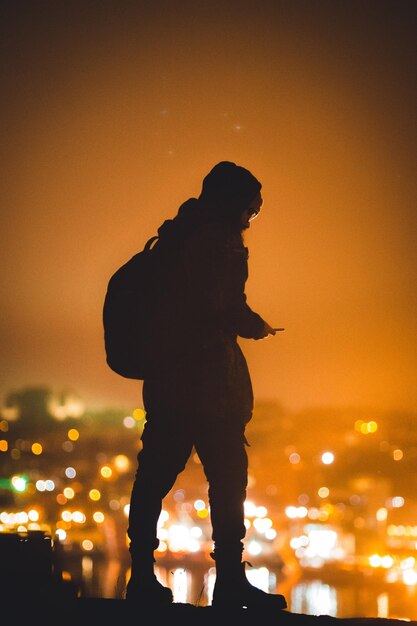 Foto silueta de un hombre de pie iluminado por las luces de la ciudad