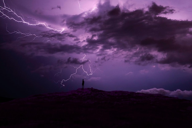 Silueta de un hombre de pie en la montaña contra una tormenta eléctrica