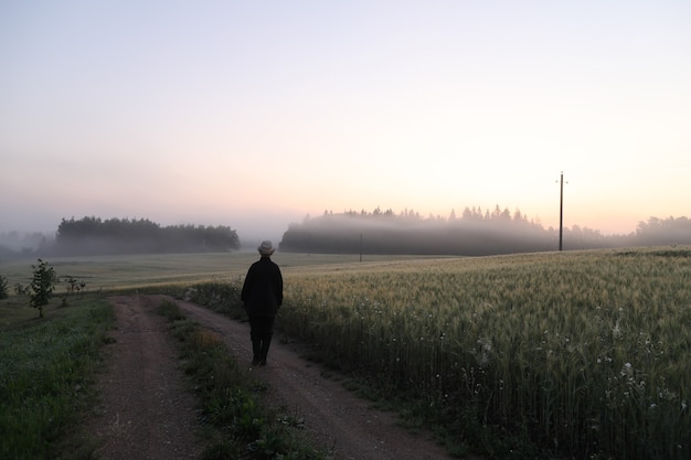 Silueta de un hombre que camina en un paisaje escénico al amanecer.