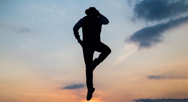 Silueta de hombre salta o vuela en el cielo del amanecer mientras habla por teléfono, comunicación.