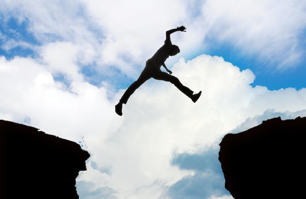 Foto silueta de un hombre saltando un acantilado 2