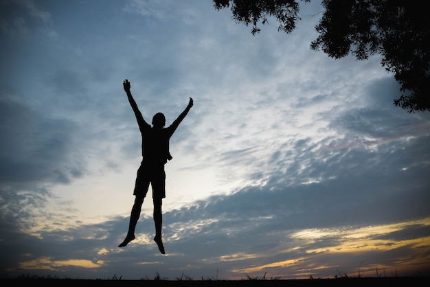 Silueta de un hombre saltando feliz en la puesta de sol.