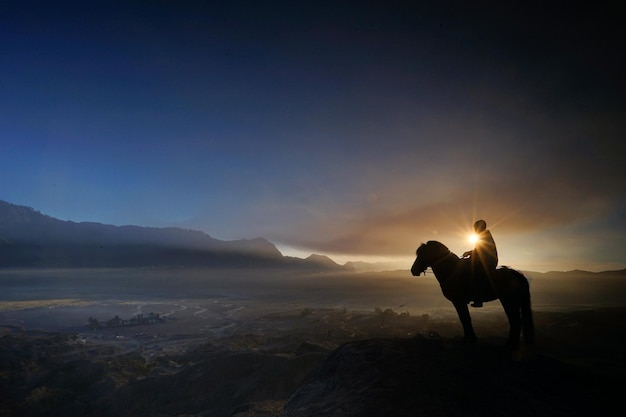 Silueta de un hombre sentado a caballo sobre una montaña