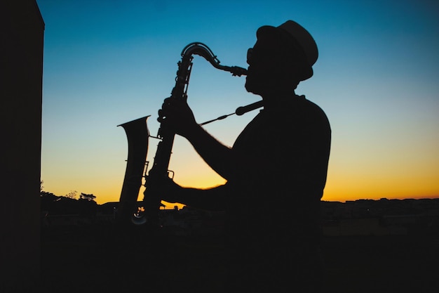 Silueta de un hombre tocando el saxofón durante la puesta de sol