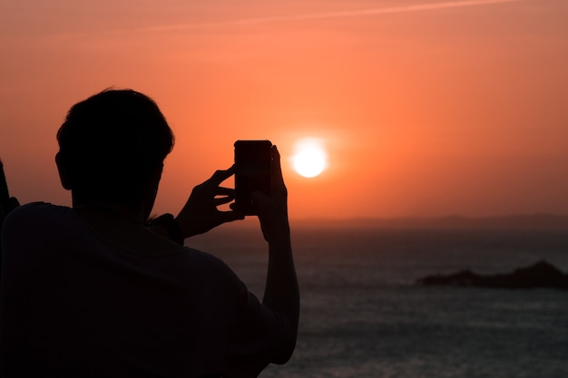 Silueta de hombre tomando fotos de la puesta de sol