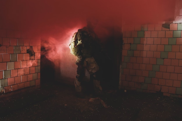 Silueta de un hombre de uniforme con un arma en un antiguo corredor de humo rojo