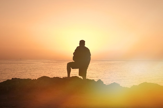 Silueta de hombre viajero al atardecer en el mar.