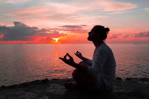 Silueta de hombre de yoga en el fondo del atardecer.