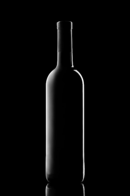 Foto silueta iluminada de una botella con vino sobre un fondo negro