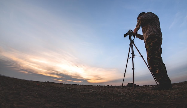 Silueta de un joven al que le gusta viajar y fotógrafo, tomando fotos de los hermosos momentos durante el atardecer, el amanecer.