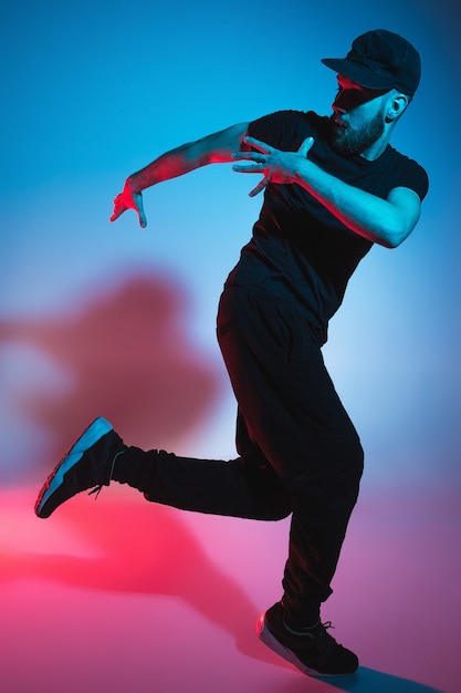 La silueta de un joven bailarín de break masculino de hip hop bailando sobre fondo de colores