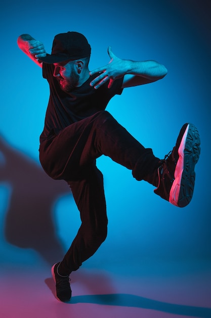 La silueta de un joven bailarín de break masculino de hip hop bailando sobre fondo de colores