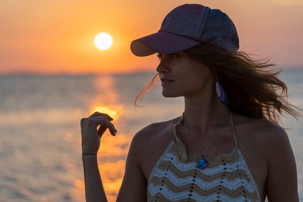 Silueta de una joven belleza en la playa tropical cerca del agua de mar en la isla paradisíaca al atardecer, de cerca. Concepto de verano. Viajes de vacaciones.