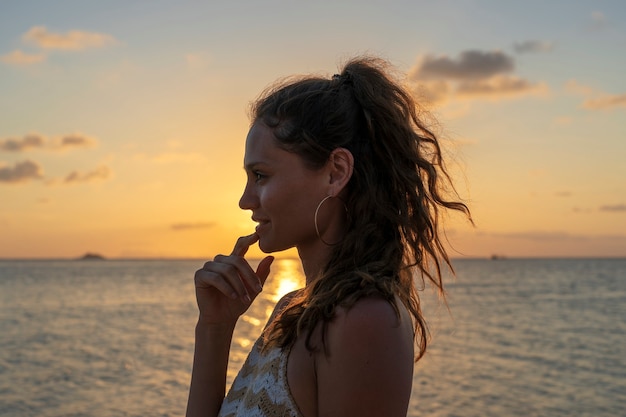 Silueta de una joven belleza en la playa tropical cerca del agua de mar en la isla paradisíaca al atardecer