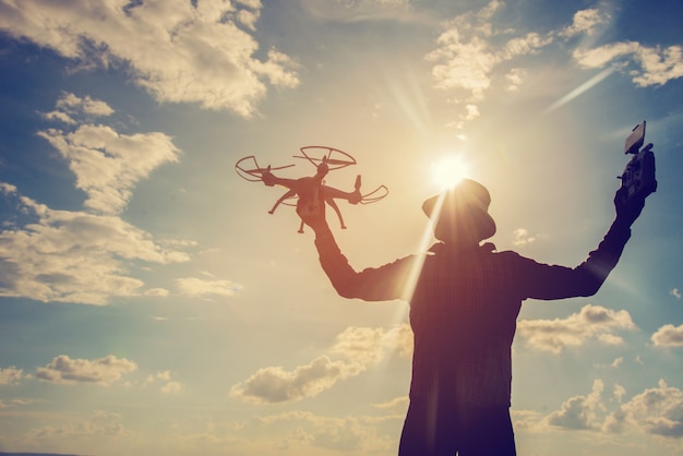 Silueta de un joven jugando con el drone al atardecer
