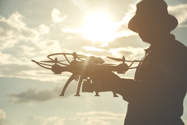 Silueta de un joven jugando con el drone al atardecer