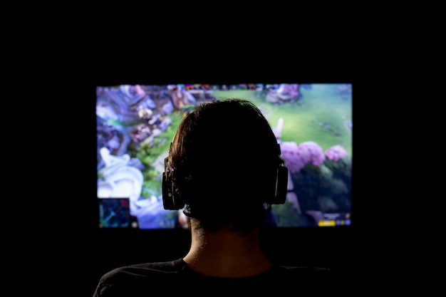 Silueta de un joven jugando videojuegos con auriculares y consola