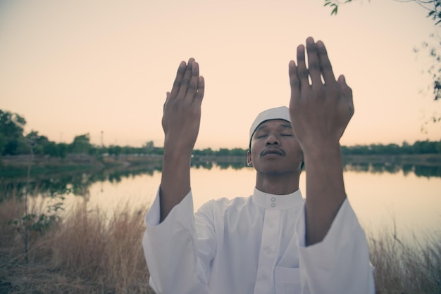 Silueta Joven musulmán asiático rezando en el concepto del festival sunsetRamadan