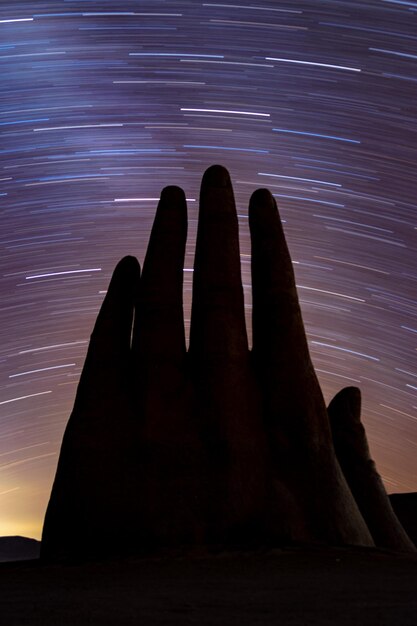 Foto la silueta de la mano contra los rastros de las estrellas por la noche