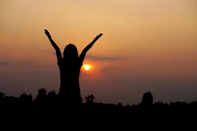 Silueta de mano humana levantada para pedir un deseo fondo de puesta de sol