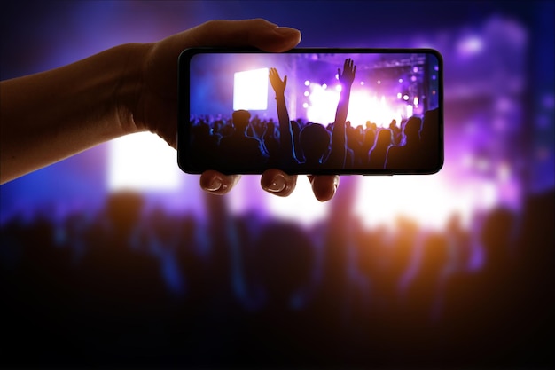 Foto silueta de mano usando un teléfono con cámara para tomar fotografías y videos en un festival de conciertos pop